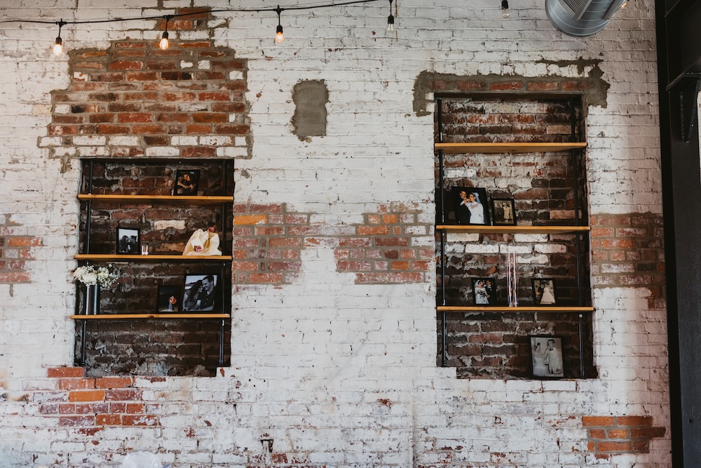 White and red brick wall with shelves holding photos