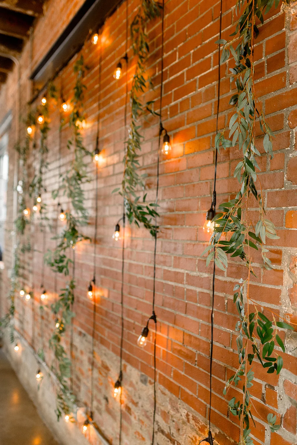 Ceremony backdrop with market lights and greenery at INDUSTRY in Indianapolis