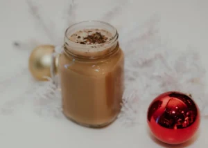 Hot chocolate in a mason jar with red and gold ornaments