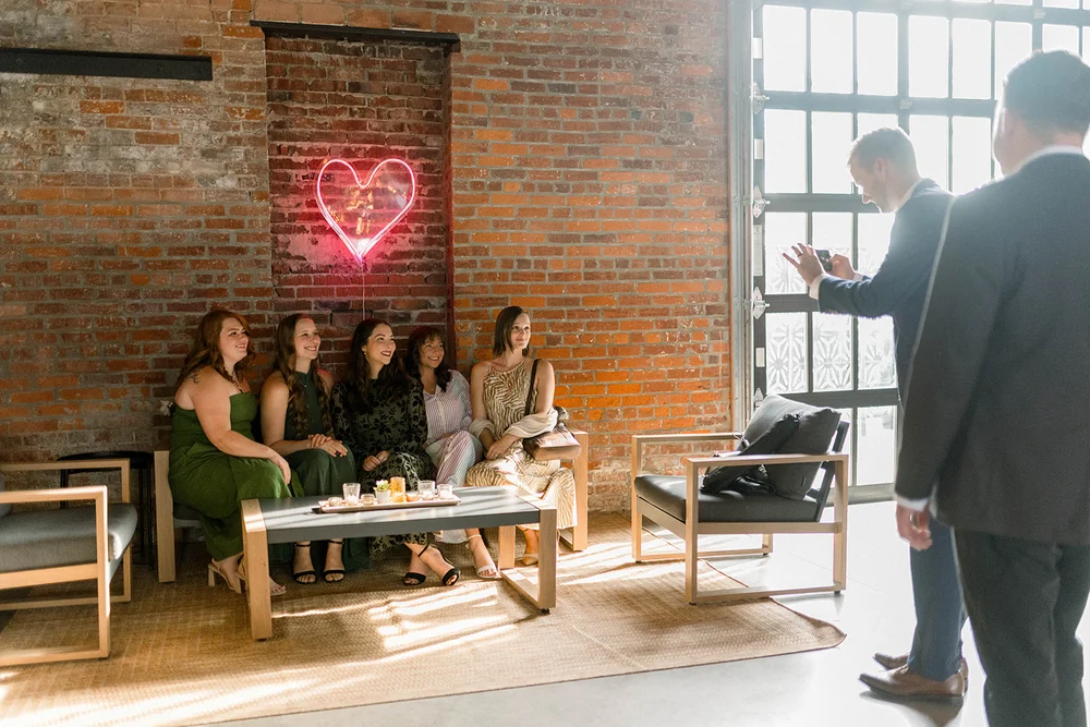 Wedding guests posing for a photo under a neon light at INDUSTRY, Indianapolis event venue