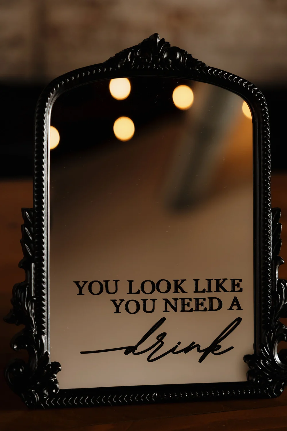 Custom mirror signage reading you look like you need a drink